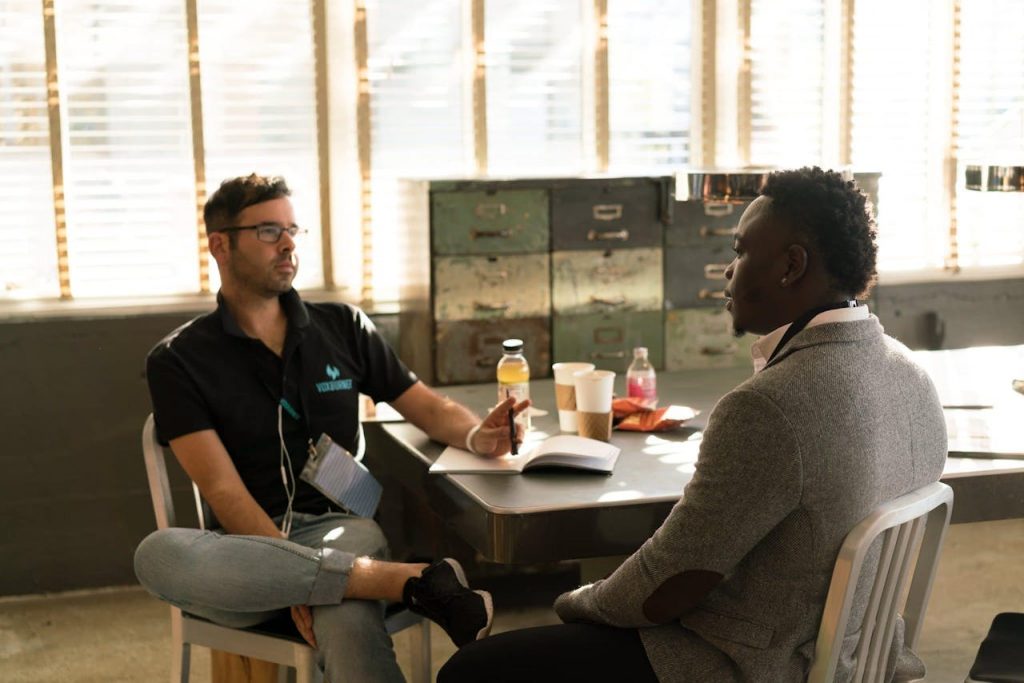 pexels-photo-935977 Two men having a focused business discussion in a sunlit office space.